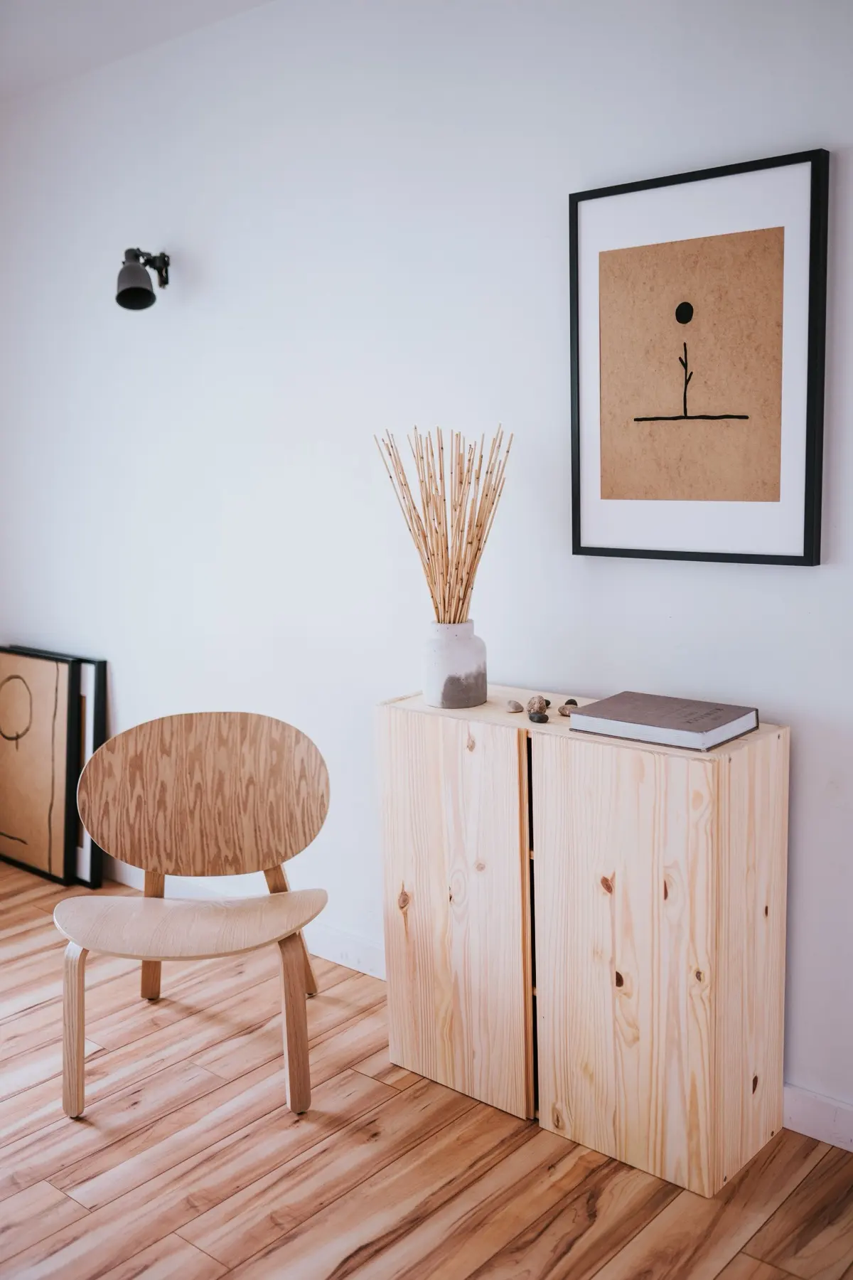 A quiet interior corner with a moulded plywood chair and daylight across a wood floor.